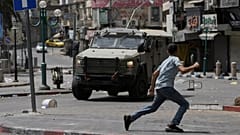 Ein Palästinenser rennt vor einem gepanzerten Fahrzeug während Zusammenstößen mit israelischen Kräften nach einem Militäreinsatz in der Stadt Nablus im Westjordanland, 27. August 2025.