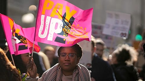 Striking teachers wave flags and show posters during a protest march in London in 2023.