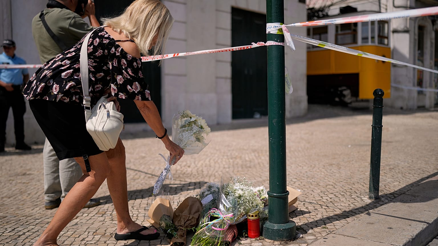 Una mujer coloca flores en el lugar donde un tranvía turístico descarriló y se estrelló en Lisboa, Portugal, el jueves 4 de septiembre de 2025.