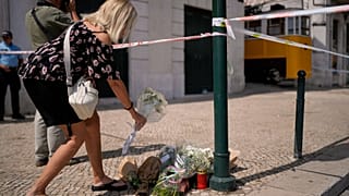 Una mujer coloca flores en el lugar donde un tranvía turístico descarriló y se estrelló en Lisboa, Portugal, el jueves 4 de septiembre de 2025.