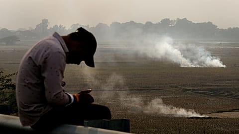 رجل يتفقد هاتفه فيما يحرق مزارعون بقايا محاصيلهم في الهند، 17 نوفمبر 2024.