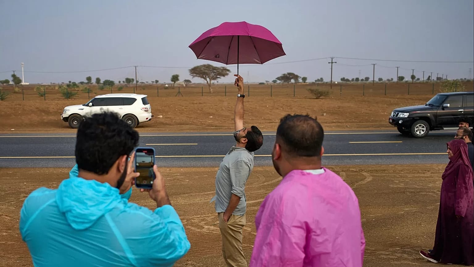 People stand in the rain as they chase rain showers at Fujairah, United Arab Emirates.
