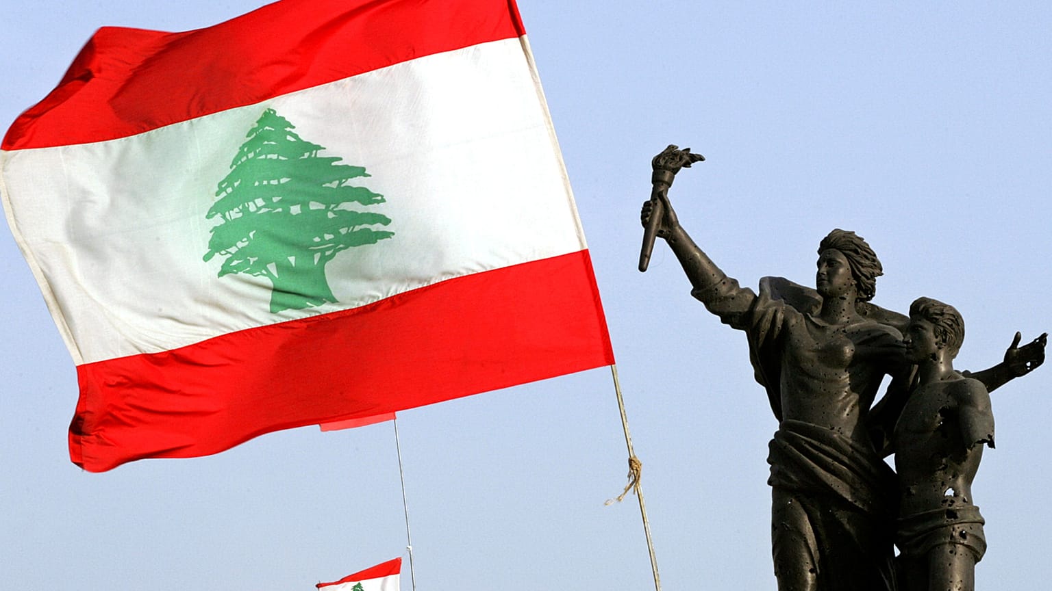 علم لبناني ضخم بجانب تمثال الشهداء المتضرر من الحرب الأهلية في وسط بيروت، لبنان،