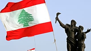 علم لبناني ضخم بجانب تمثال الشهداء المتضرر من الحرب الأهلية في وسط بيروت، لبنان،