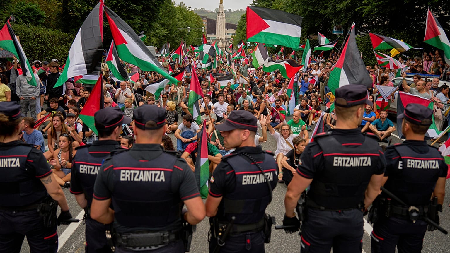 أشخاص يحملون الأعلام الفلسطينية يجلسون في الشارع بعد تعطيل المرحلة الحادية عشرة من سباق فويلتا الإسباني للدراجات في بلباو 3 سبتمبر 2025