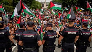 أشخاص يحملون الأعلام الفلسطينية يجلسون في الشارع بعد تعطيل المرحلة الحادية عشرة من سباق فويلتا الإسباني للدراجات في بلباو 3 سبتمبر 2025