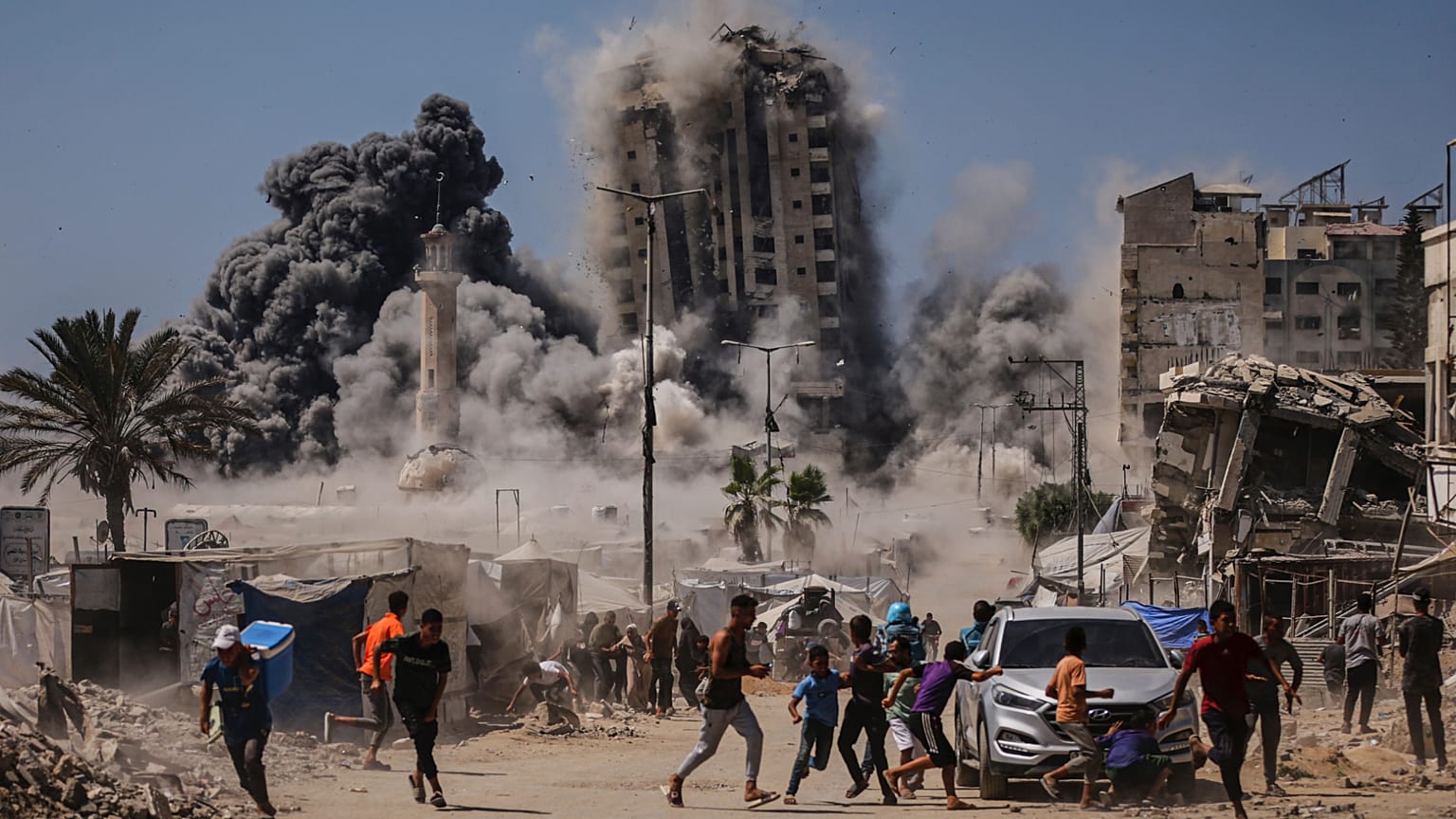 فلسطينيون يركضون للاحتماء أثناء غارة جوية إسرائيلية على برج في مدينة غزة بعد أن أصدر الجيش الإسرائيلي تحذيراً مسبقاً، الجمعة 5 سبتمبر/ أيلول 2025.