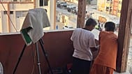 تظهر هذه الصورة، الملتقطة في 13 أغسطس/ آب 2025، مصور رويترز حسام المصري، مرتديًا قميصًا أبيض، واقفا بجوار كاميرا الفيديو الخاصة به المغطاة بمنشفة على درج مستشفى ناصر.