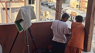 تظهر هذه الصورة، الملتقطة في 13 أغسطس/ آب 2025، مصور رويترز حسام المصري، مرتديًا قميصًا أبيض، واقفا بجوار كاميرا الفيديو الخاصة به المغطاة بمنشفة على درج مستشفى ناصر.