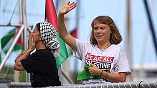 الناشطة المناخية السويدية غريتا ثونبرغ تلوح من قارب يشارك في أسطول مدني متجه إلى غزة، بهدف كسر الحصار الإسرائيلي في برشلونة، إسبانيا، الأحد 31 أغسطس/ آب 2025.
