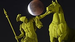 Der Vollmond geht während der totalen Mondfinsternis hinter einer Skulptur auf dem Palastplatz in St. Petersburg auf.