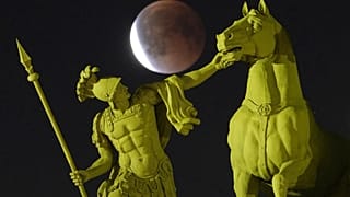 Der Vollmond geht während der totalen Mondfinsternis hinter einer Skulptur auf dem Palastplatz in St. Petersburg auf.