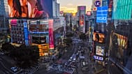 FILE - People walk across the famed Shibuya scramble crossing as the sun sets behind the skyscraper Monday, 11. October, 2021, in Tokyo.
