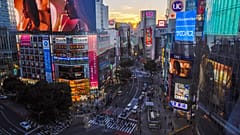DOSYA - 11 Ekim 2021 Pazartesi günü Tokyo'da gökdelenin arkasında güneş batarken insanlar ünlü Shibuya kavşağında yürüyor. Ekim, 2021, Tokyo.