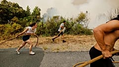 Moradores locais e voluntários trabalham em conjunto para apagar um incêndio florestal em Larouco, no noroeste de Espanha.