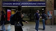 Os passageiros passam pela entrada fechada da estação de metro de London Bridge durante uma greve
