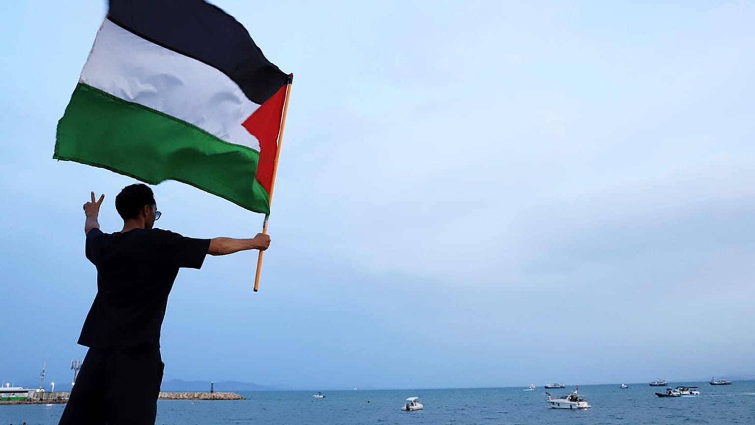 متظاهر يلوح بعلم فلسطيني لدعم أسطول الصمود العالمي عند وصوله إلى ميناء سيدي بوسعد في تونس العاصمة ، تونس ، الأحد ، سبتمبر. 7, 2025. 