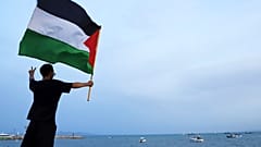 متظاهر يلوح بعلم فلسطيني لدعم أسطول الصمود العالمي عند وصوله إلى ميناء سيدي بوسعد في تونس العاصمة ، تونس ، الأحد ، سبتمبر. 7, 2025. 