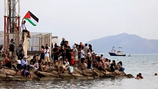 Protesters wave a Palestinian flag in support of the Global Sumud Flotilla as it arrives at the port of Sidi Bou Saïd, 7 September, 2025