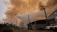 Un avión de extinción de incendios arroja agua sobre un incendio forestal en Veiga das Meas, en el noroeste de España, el sábado 16 de agosto de 2025.