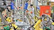 A worker assembles vehicle parts on a production line inside Renault factory.