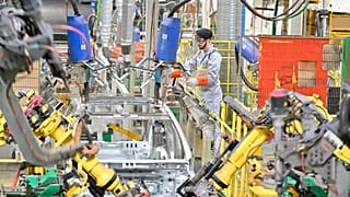 A worker assembles vehicle parts on a production line inside Renault factory.