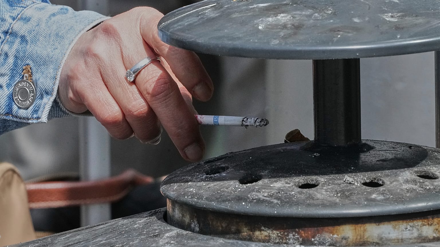 A woman places the ashes of her cigarette in an ashtray in France in a file photo.
