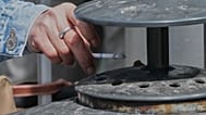 Una mujer deposita las cenizas de su cigarrillo en un cenicero en Francia en una foto de archivo.