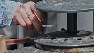 Una mujer deposita las cenizas de su cigarrillo en un cenicero en Francia en una foto de archivo.