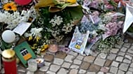 Postkarten aus Lissabon liegen zwischen den Blumen, die zum Gedenken an die Opfer des Unglücks der Gloria-Standseilbahn niedergelegt wurden.