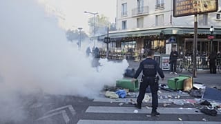 Un policier se tient à côté de poubelles placées dans une rue pour la bloquer lors du mouvement de protestation « Bloquons Tout » à Paris, mercredi 10 septembre 2025.