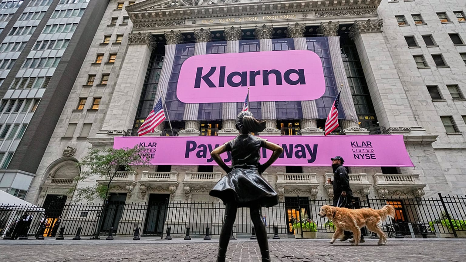 The Fearless Girl statue faces the facade of the New York Stock Exchange that displays signage for Sweden's Klarna. 10 September 2025.