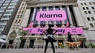 The Fearless Girl statue faces the facade of the New York Stock Exchange that displays signage for Sweden's Klarna. 10 September 2025.