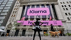 The Fearless Girl statue faces the facade of the New York Stock Exchange that displays signage for Sweden's Klarna. 10 September 2025.