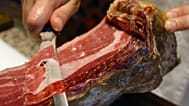 Archivo: Un hombre corta un jamón ibérico en Alburquerque, suroeste de España.