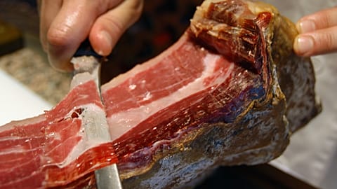 File: A man cuts an Iberian ham in Alburquerque, southwestern Spain. 