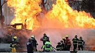 Firefighters spray hoses at a gas tanker that exploded