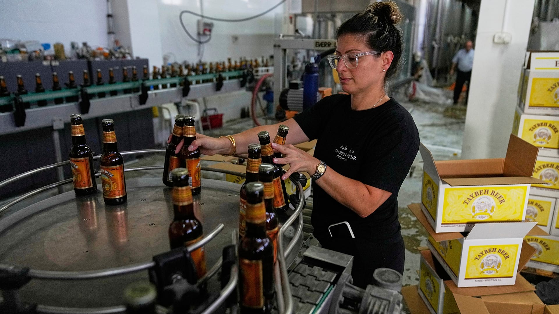 Nadin Khoury embala produtos da cerveja Taybeh numa linha de produção da empresa familiar palestiniana Taybeh Brewery Co. na cidade de Taybeh, na Cisjordânia. 6 de setembro de 2025.