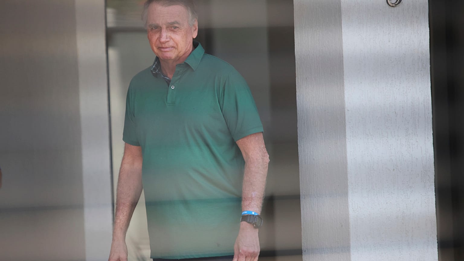Brazil's former President Jair Bolsonaro stands at the entrance of his home where he is under house arrest in Brasilia, Brazil, Thursday, Sept. 11, 2025. (AP Photo/Luis Nova)
