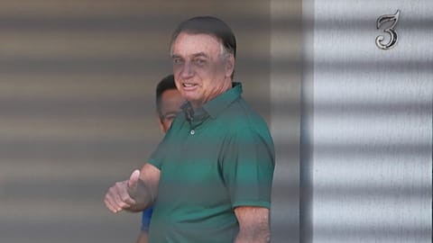Brazil's former President Jair Bolsonaro flashes a thumbs up while standing at the entrance of his home where he is under house arrest, Brasilia, Brazil, Sept. 11, 2025