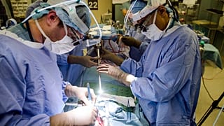 Dos doctores visualizan el tumor de un paciente en monitores mientras realizan una cirugía