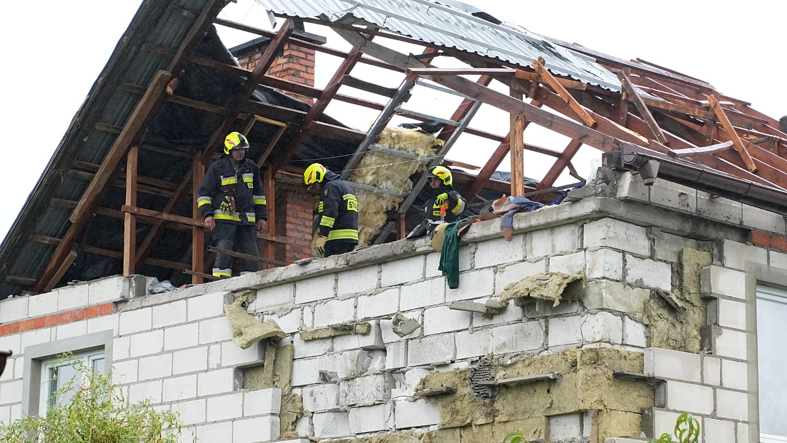 Feuerwehrleute auf einem zerstörten Dach, um ein beschädigtes Haus in Wyryki zu untersuchen.