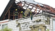 Feuerwehrleute auf einem zerstörten Dach, um ein beschädigtes Haus in Wyryki zu untersuchen.