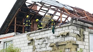 Feuerwehrleute auf einem zerstörten Dach, um ein beschädigtes Haus in Wyryki zu untersuchen.