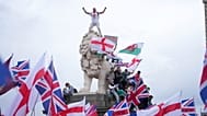 A demonstrator stands on the head of one of the lions of Westminster Bridge during a Tommy Robinson-led Unite the Kingdom march and rally in London, Saturday Sept. 13, 2025.
