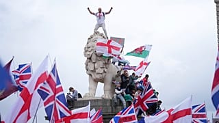 A demonstrator stands on the head of one of the lions of Westminster Bridge during a Tommy Robinson-led Unite the Kingdom march and rally in London, Saturday Sept. 13, 2025.