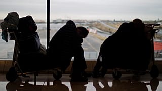 Dos pasajeros duermen en carritos de equipaje en el Aeropuerto de Barajas, Madrid, el domingo 5 de diciembre de 2010.