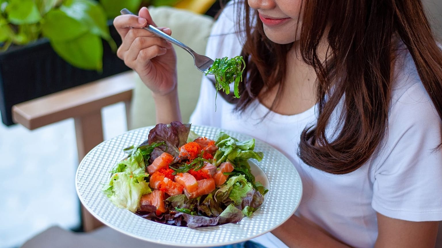 A woman eats a salad.