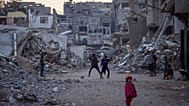 Palestinian children play next to buildings destroyed by Israeli army strikes