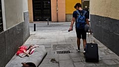 Un turista pasa junto a una mujer sin hogar en el centro de Madrid, España, el martes 3 de junio de 2025.